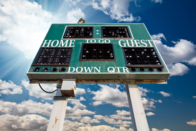 HIgh School Scoreboard Over Blue Sky with Clouds and Sun Rays.