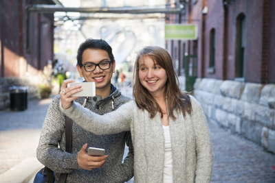 Two young people taking a selfie with smartphone