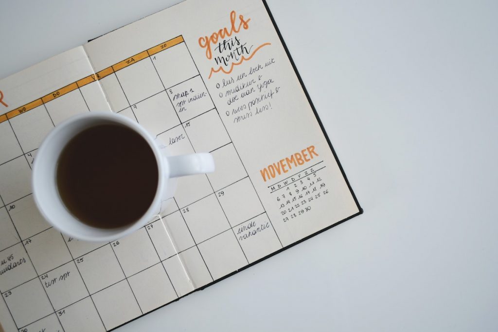 Coffee mug on top of an opened monthly planner