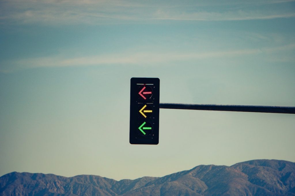 Stop light with red, yellow, and green arrows with mountains in the background