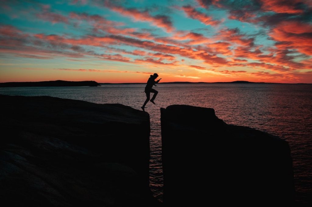 Man jumping between rocks near the ocean